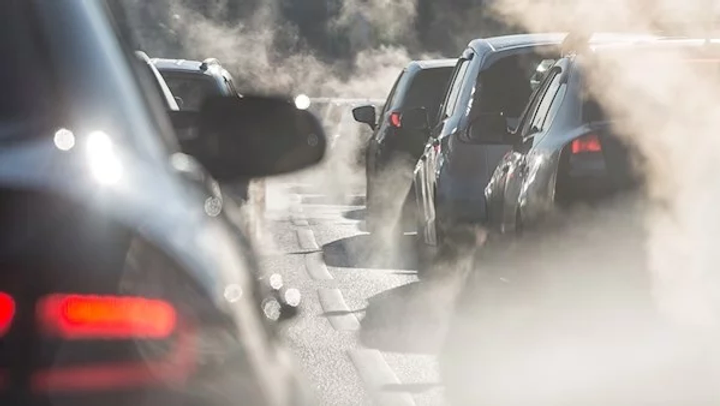 Que of cars stuck in traffic, surrounded by exhaust fumes